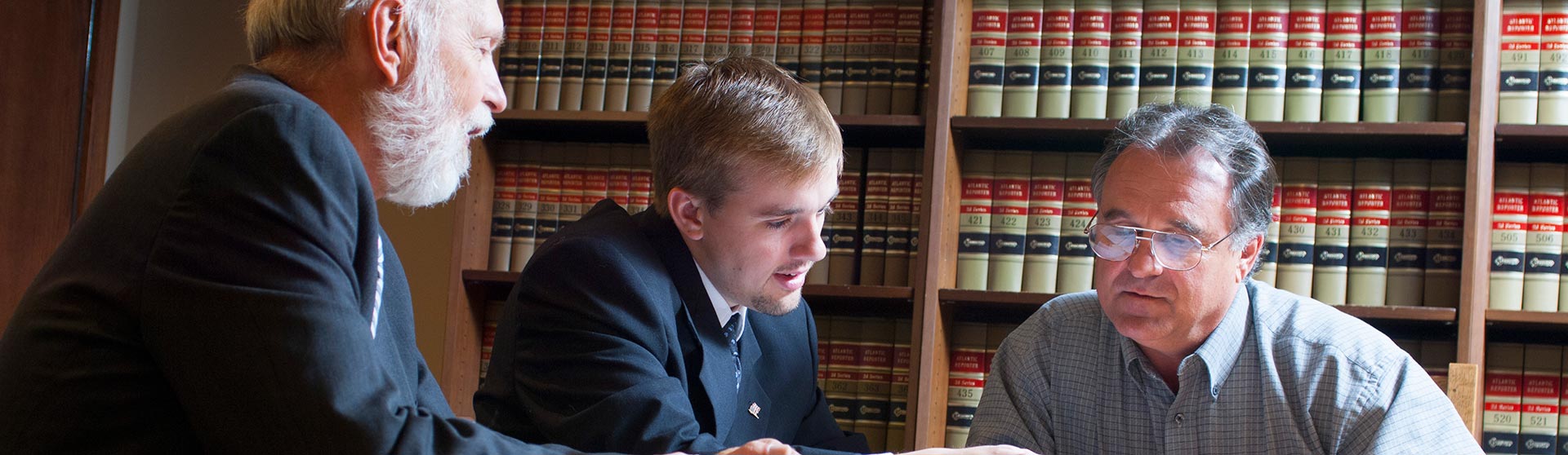 Three people looking at a text book
