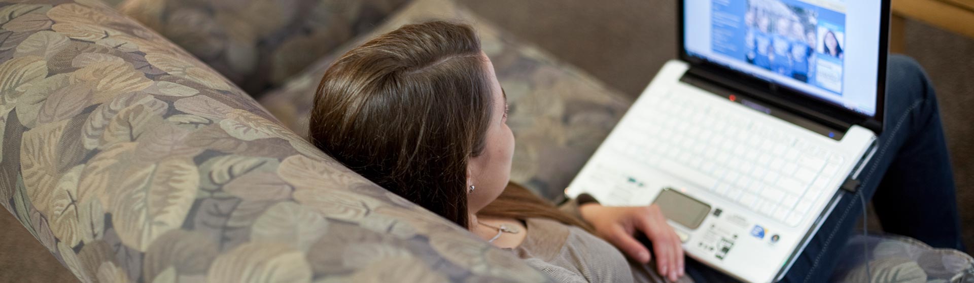 A woman on a couch looking at a laptop.
