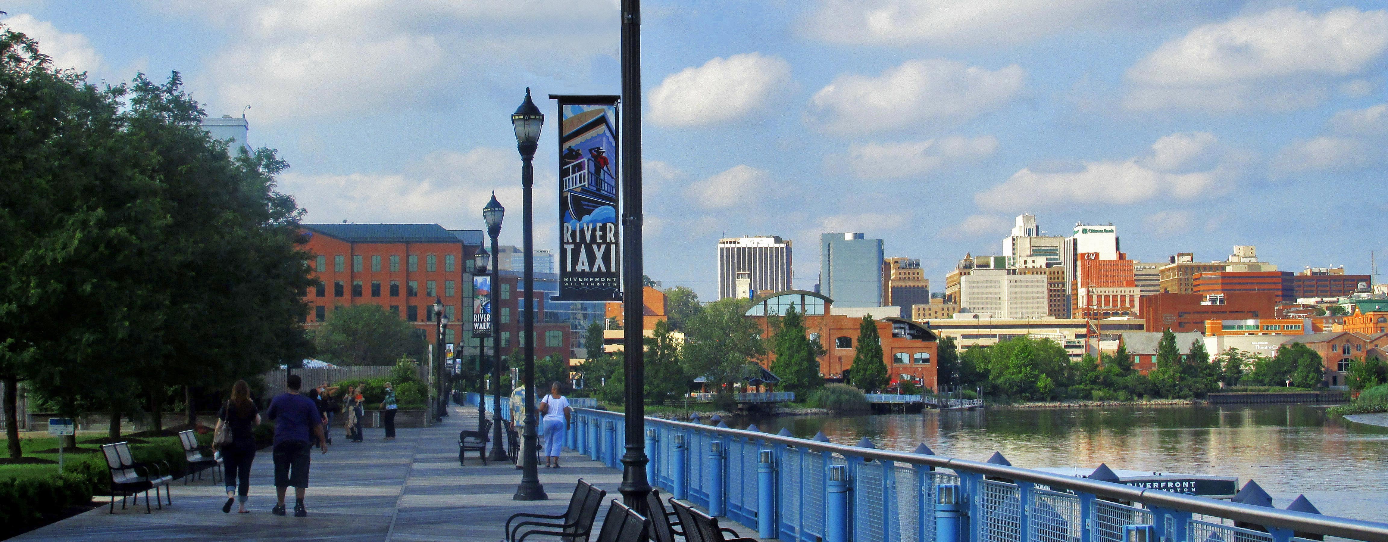 People walking along a sidewalk next to the Delaware River.